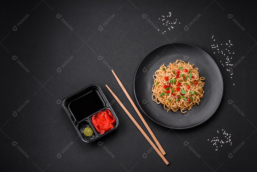 Delicioso macarrão asiático fresco com legumes, sal, especiarias e ervas em uma placa cerâmica sobre um fundo escuro de concreto