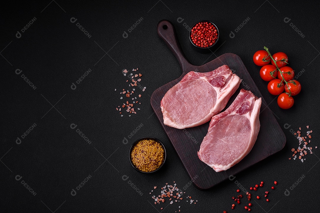 Carne de porco crua com osso ou costela cortada com sal, especiarias e ervas sobre um fundo escuro de concreto