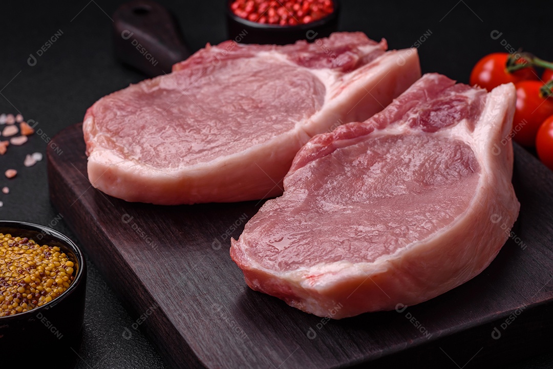 Carne de porco crua com osso ou costela cortada com sal, especiarias e ervas sobre um fundo escuro de concreto