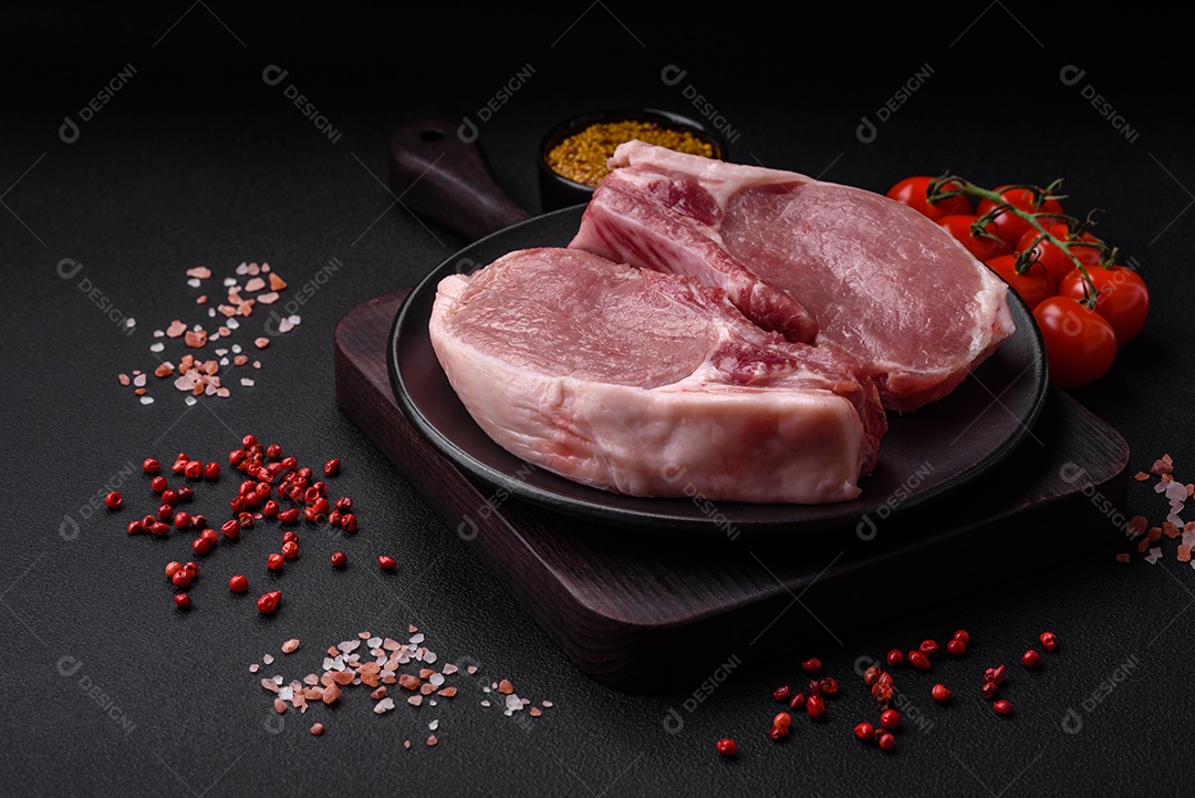 Carne de porco crua com osso ou costela cortada com sal, especiarias e ervas sobre um fundo escuro de concreto