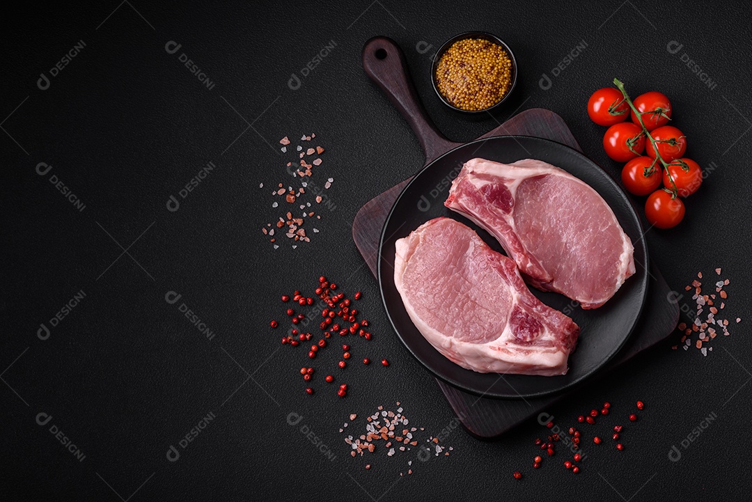 Carne de porco crua com osso ou costela cortada com sal, especiarias e ervas sobre um fundo escuro de concreto