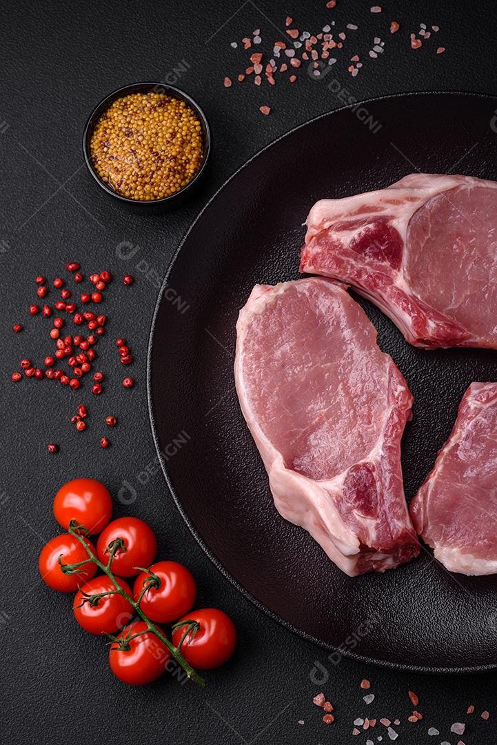 Carne de porco crua com osso ou costela cortada com sal, especiarias e ervas sobre um fundo escuro de concreto