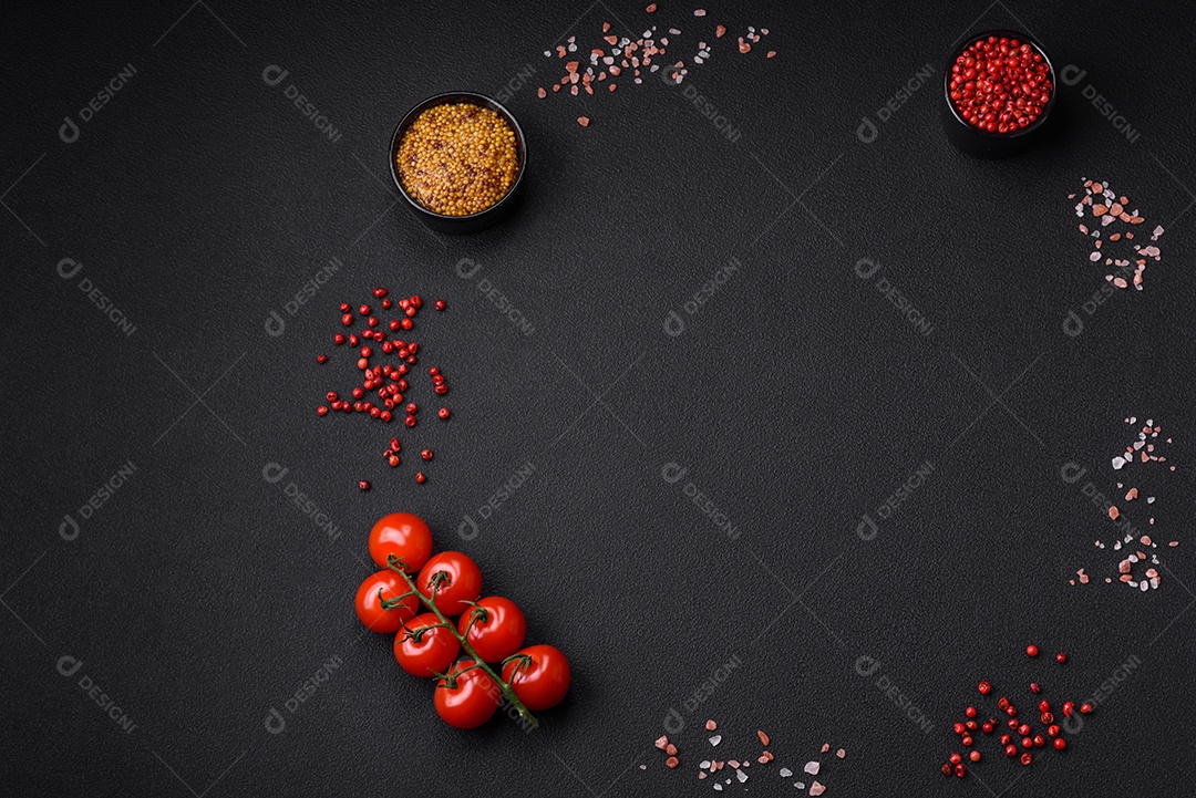 Mesa vazia de textura preta, tomate cereja em um galho, especiarias, sal e ervas. Ingredientes para cozinhar em casa