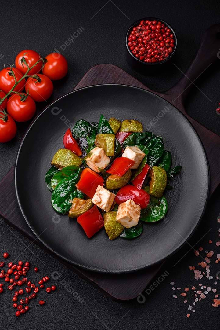 Deliciosa salada fresca de abobrinha, queijo, pimentão, espinafre com especiarias e ervas em um prato de cerâmica sobre um fundo escuro de concreto