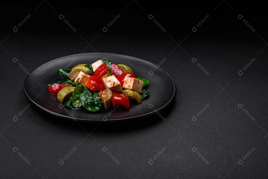 Deliciosa salada fresca de abobrinha, queijo, pimentão, espinafre com especiarias e ervas em um prato de cerâmica sobre um fundo escuro de concreto