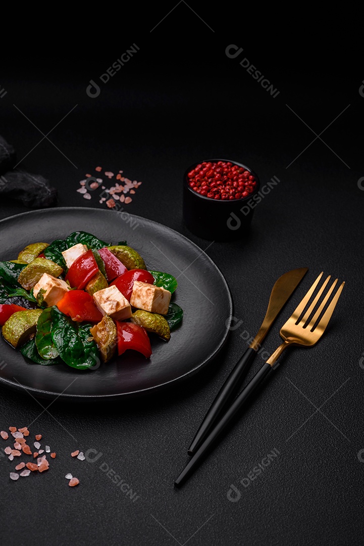 Deliciosa salada fresca de abobrinha, queijo, pimentão, espinafre com especiarias e ervas em um prato de cerâmica sobre um fundo escuro de concreto