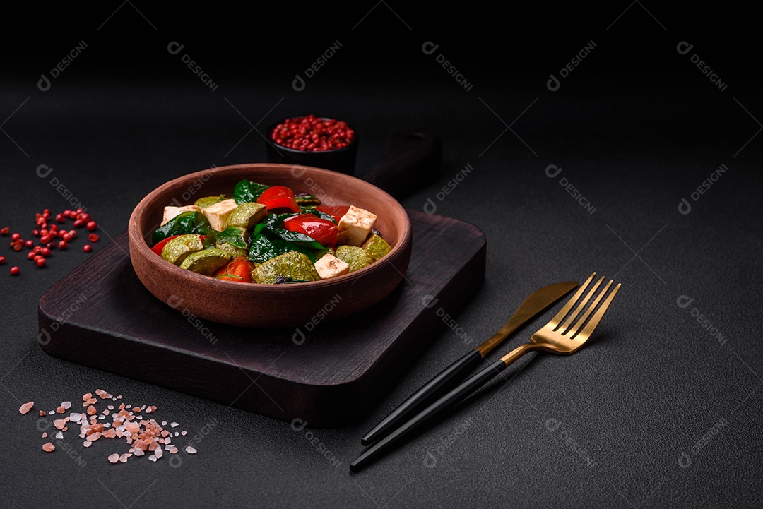 Deliciosa salada fresca de abobrinha, queijo, pimentão, espinafre com especiarias e ervas em um prato de cerâmica sobre um fundo escuro de concreto