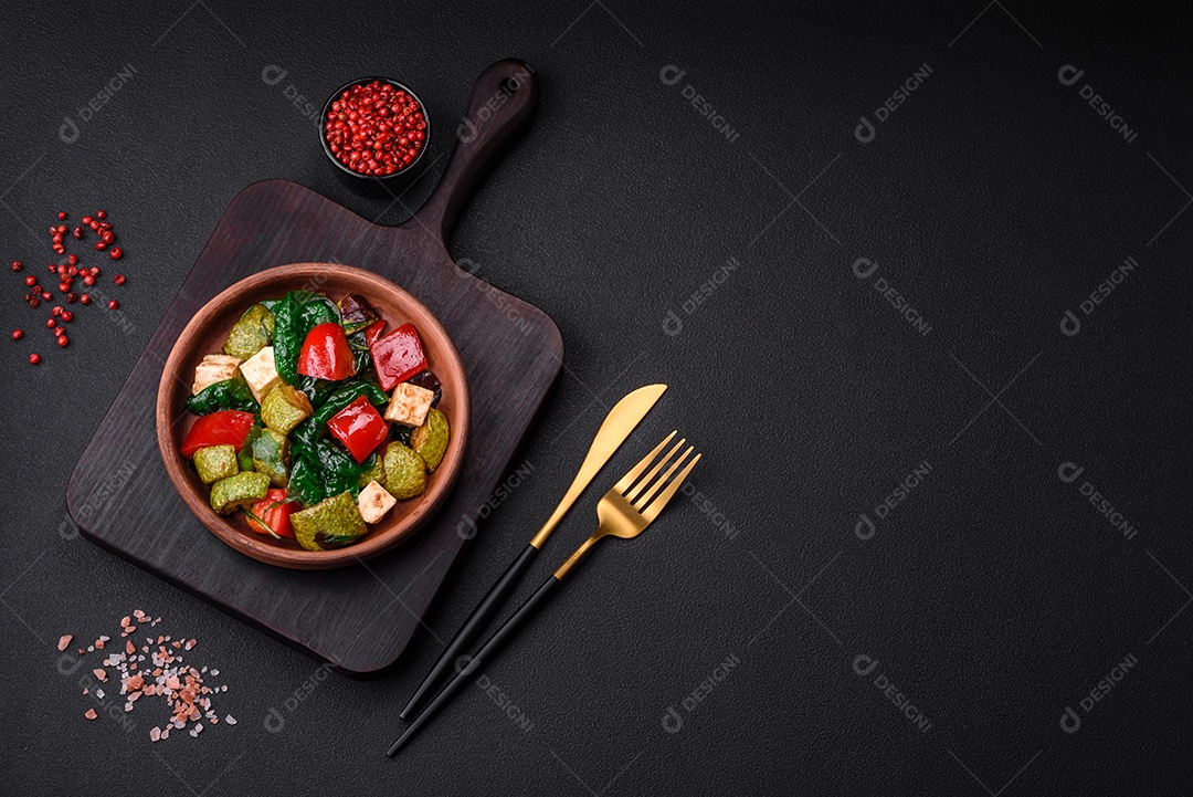 Deliciosa salada fresca de abobrinha, queijo, pimentão, espinafre com especiarias e ervas em um prato de cerâmica sobre um fundo escuro de concreto