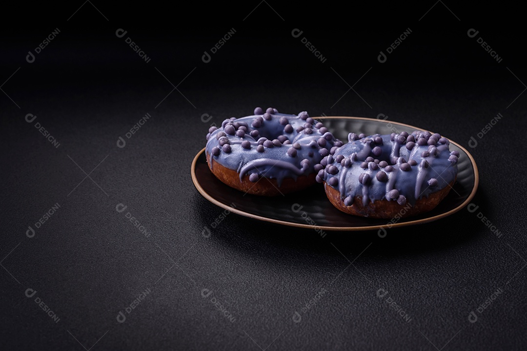 Delicioso donut doce de cor roxa em esmalte e com bolas lilás com recheio de chocolate sobre um fundo escuro de concreto