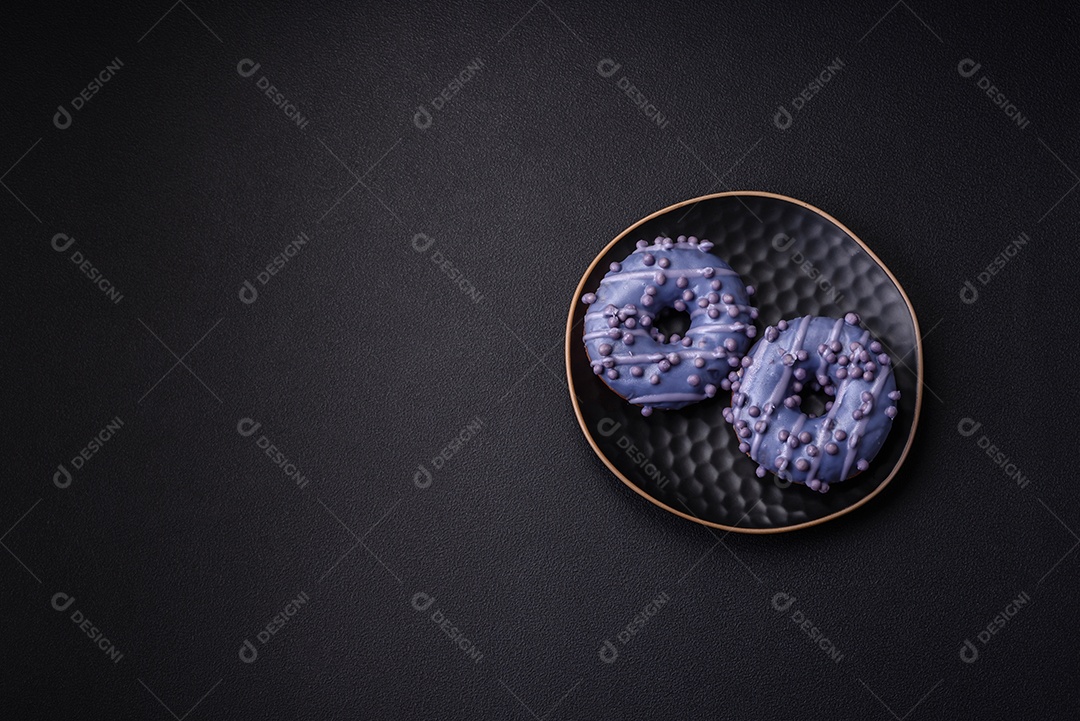 Delicioso donut doce de cor roxa em esmalte e com bolas lilás com recheio de chocolate sobre um fundo escuro de concreto