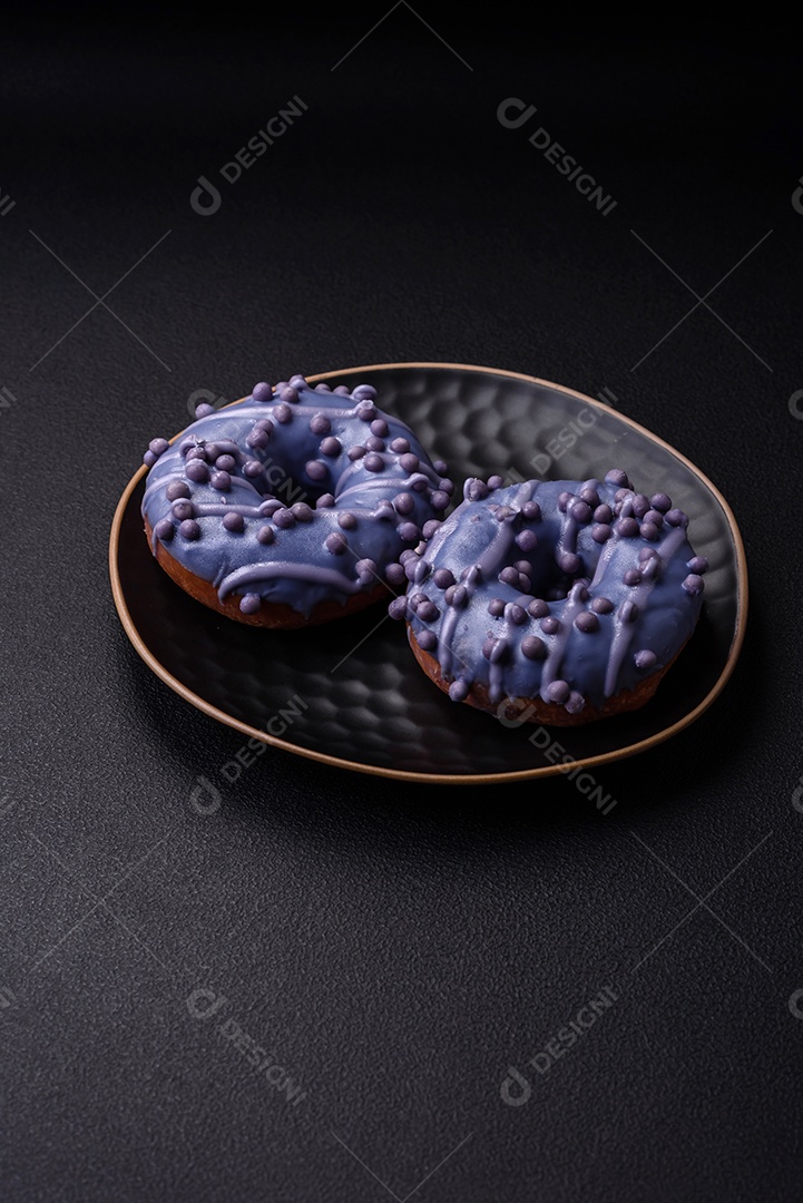 Delicioso donut doce de cor roxa em esmalte e com bolas lilás com recheio de chocolate sobre um fundo escuro de concreto