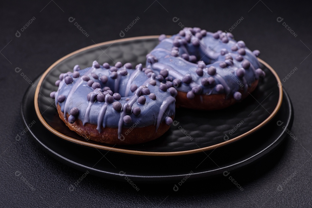 Delicioso donut doce de cor roxa em esmalte e com bolas lilás com recheio de chocolate sobre um fundo escuro de concreto