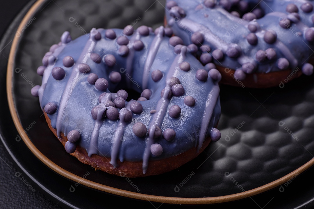 Delicioso donut doce de cor roxa em esmalte e com bolas lilás com recheio de chocolate sobre um fundo escuro de concreto