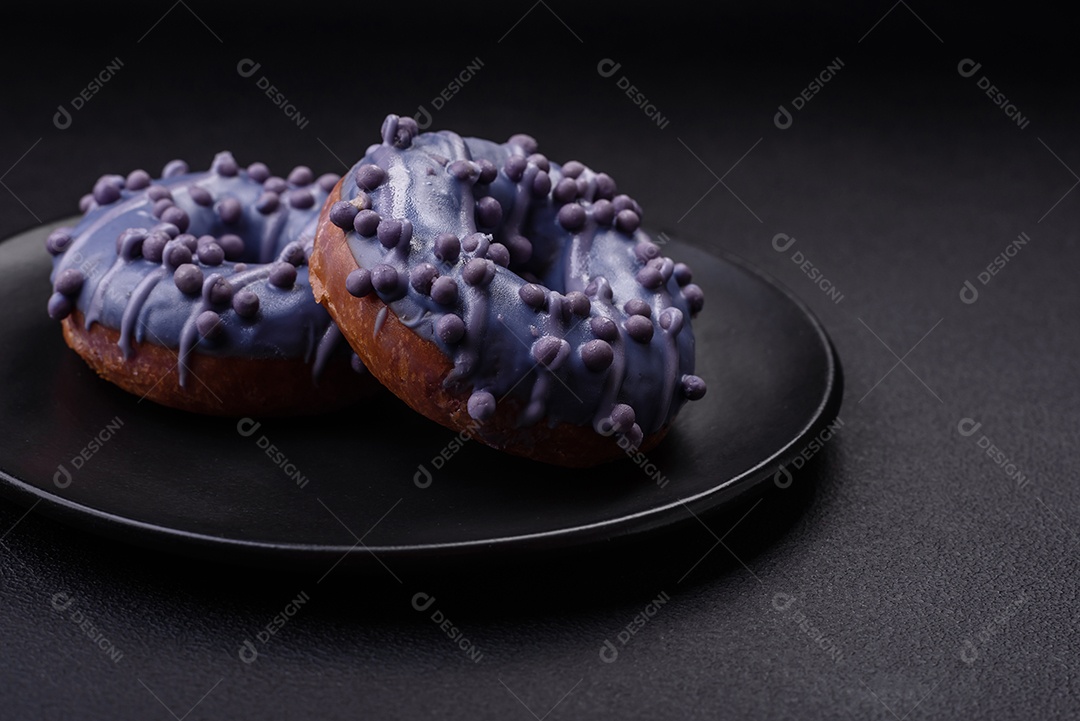 Delicioso donut doce de cor roxa em esmalte e com bolas lilás com recheio de chocolate sobre um fundo escuro de concreto