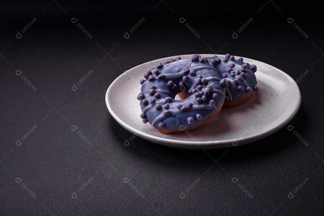 Delicioso donut doce de cor roxa em esmalte e com bolas lilás com recheio de chocolate sobre um fundo escuro de concreto