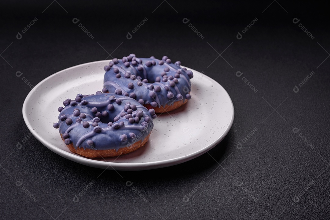 Delicioso donut doce de cor roxa em esmalte e com bolas lilás com recheio de chocolate sobre um fundo escuro de concreto