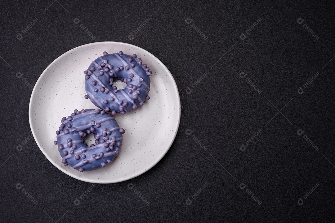 Delicioso donut doce de cor roxa em esmalte e com bolas lilás com recheio de chocolate sobre um fundo escuro de concreto