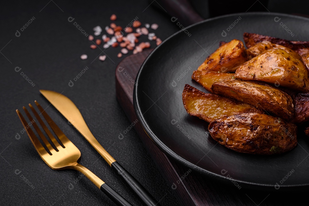 Deliciosas fatias de batata grelhada com alho, especiarias e ervas sobre um fundo escuro de concreto