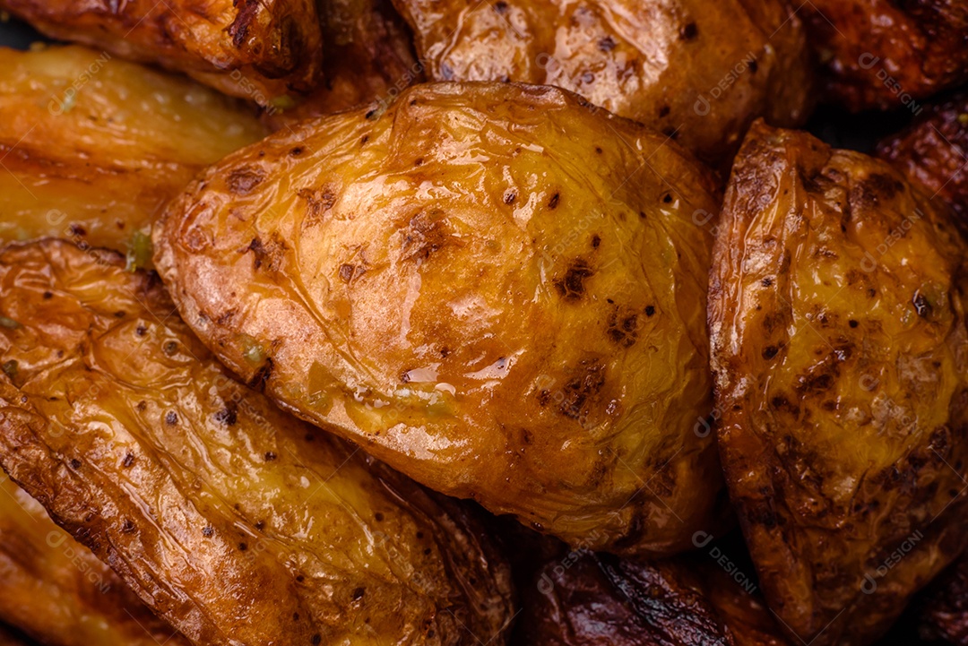 Deliciosas fatias de batata grelhada com alho, especiarias e ervas sobre um fundo escuro de concreto