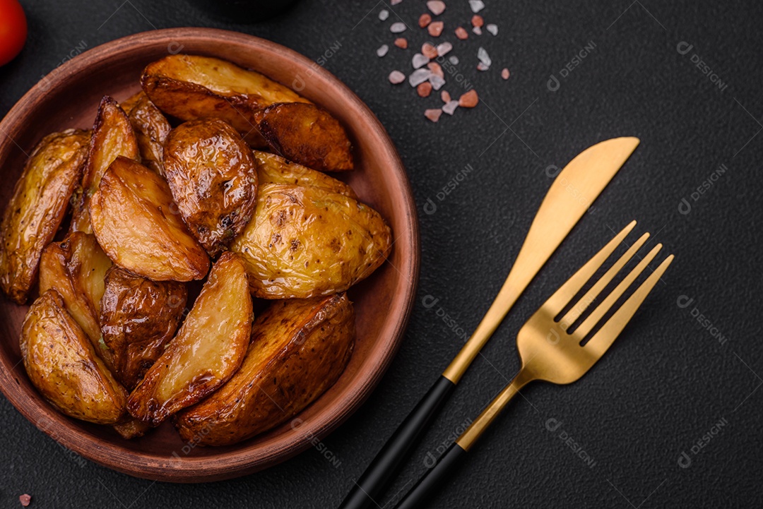 Deliciosas fatias de batata grelhada com alho, especiarias e ervas sobre um fundo escuro de concreto