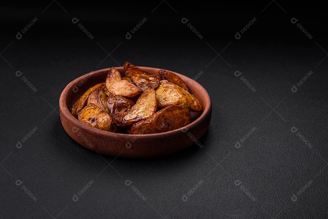 Deliciosas fatias de batata grelhada com alho, especiarias e ervas sobre um fundo escuro de concreto