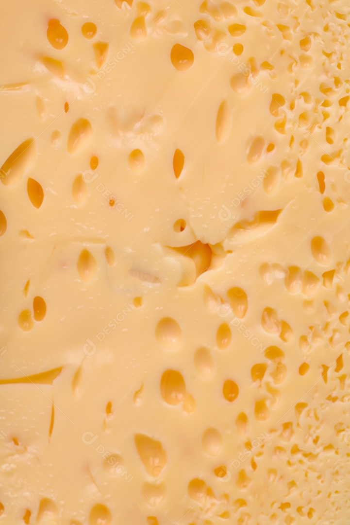 Delicioso queijo amarelo poroso cortado em pedaços grandes numa placa cerâmica sobre um fundo escuro de concreto