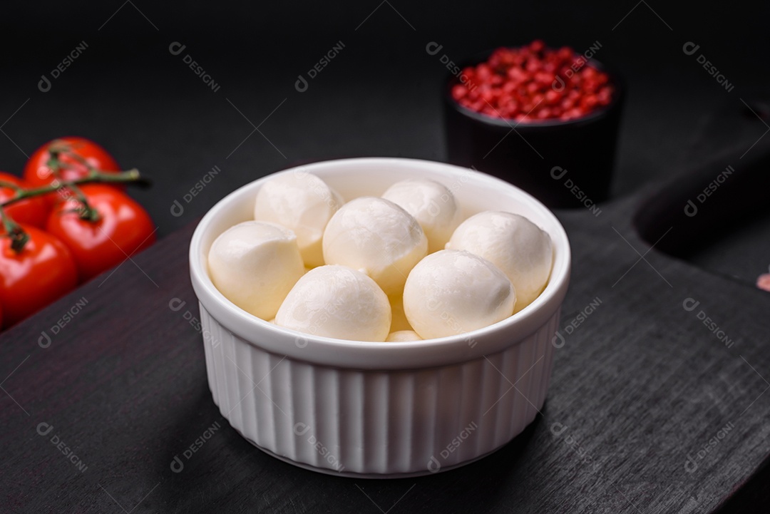 Delicioso queijo mussarela fresco em forma de bolinhas com sal e especiarias sobre fundo escuro de concreto