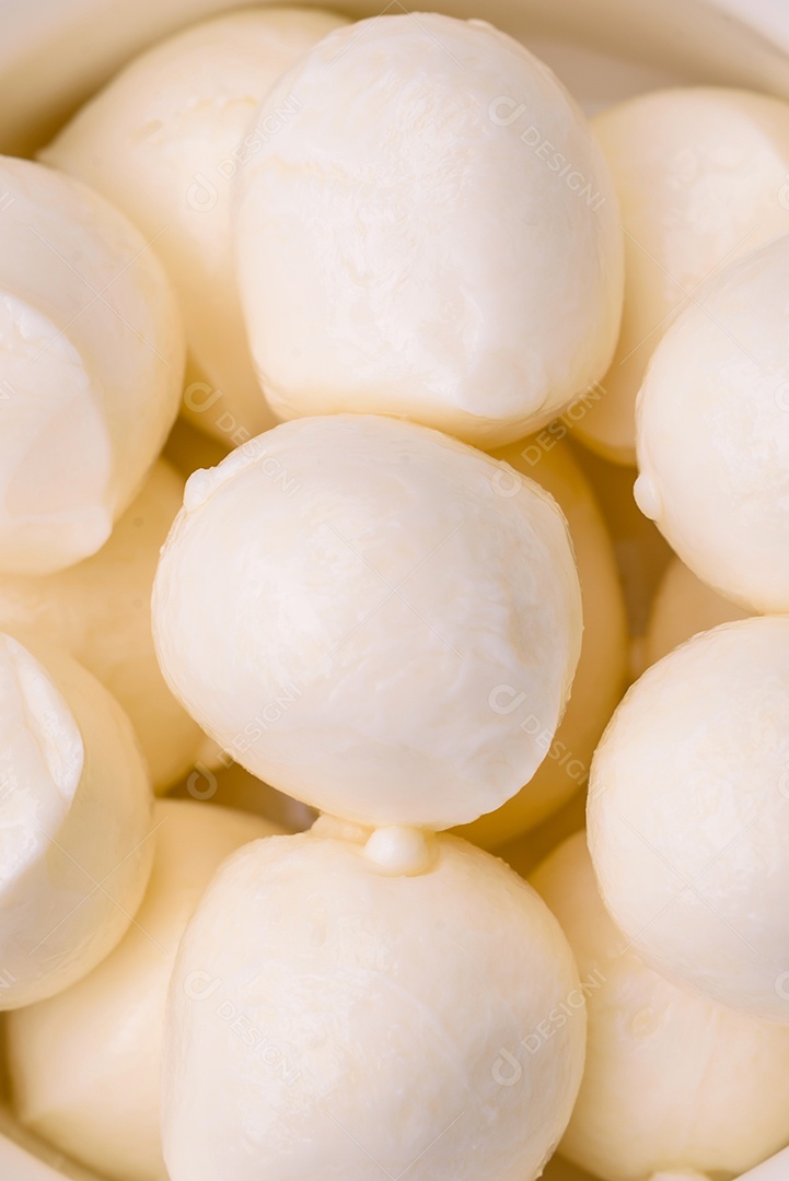 Delicioso queijo mussarela fresco em forma de bolinhas com sal e especiarias sobre fundo escuro de concreto