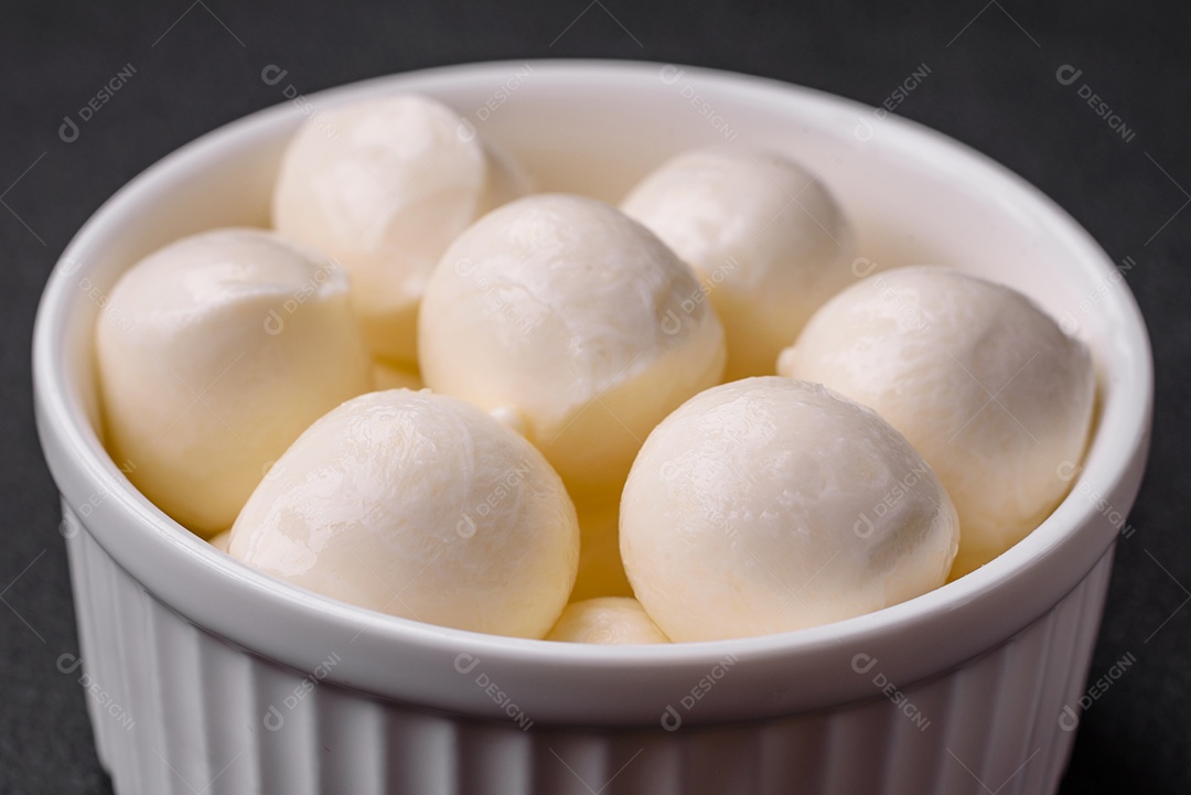 Delicioso queijo mussarela fresco em forma de bolinhas com sal e especiarias sobre fundo escuro de concreto