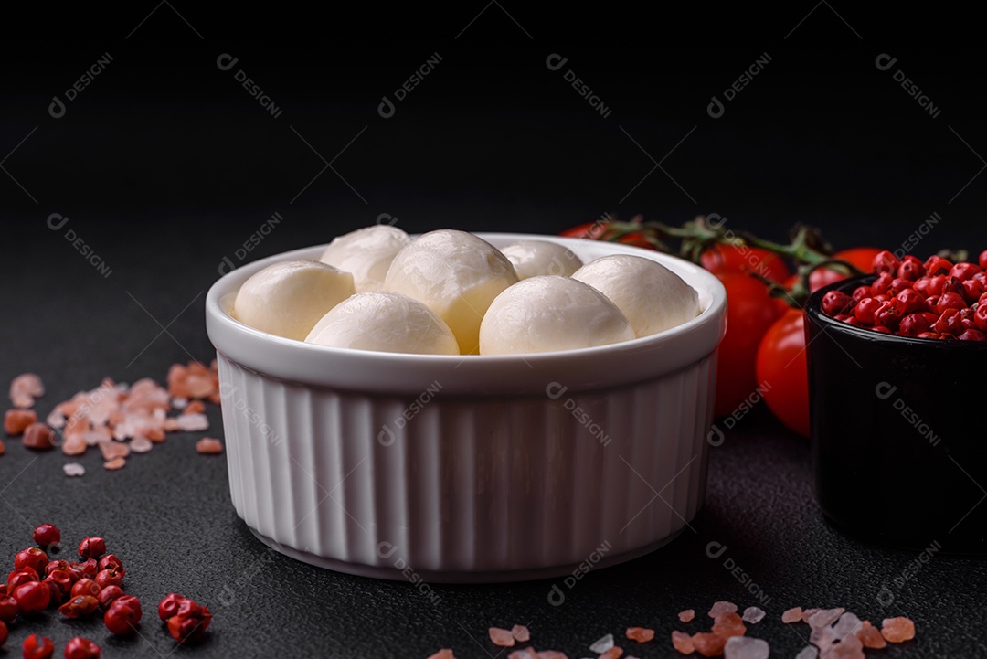 Delicioso queijo mussarela fresco em forma de bolinhas com sal e especiarias sobre fundo escuro de concreto