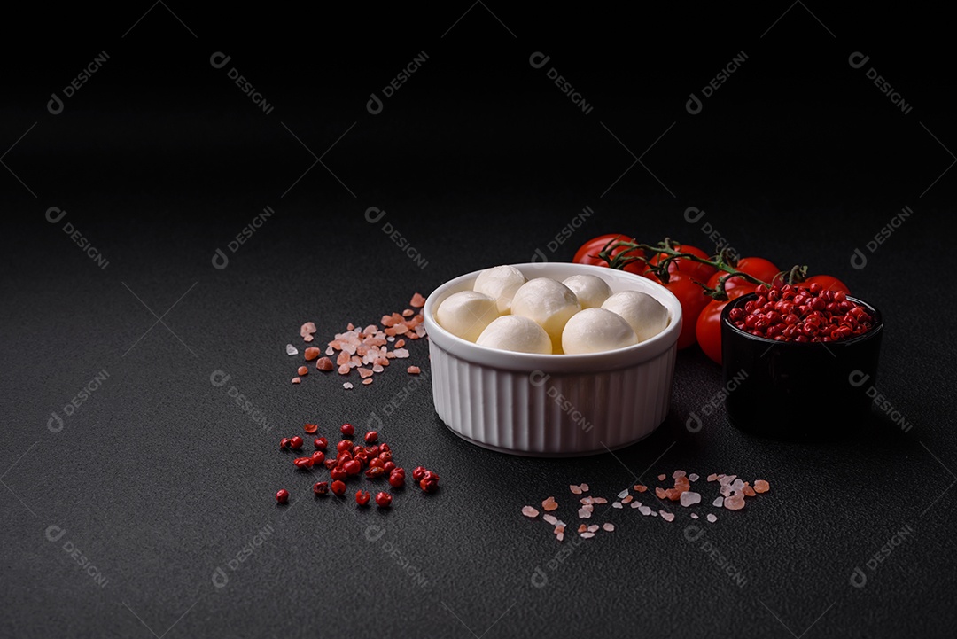 Delicioso queijo mussarela fresco em forma de bolinhas com sal e especiarias sobre fundo escuro de concreto