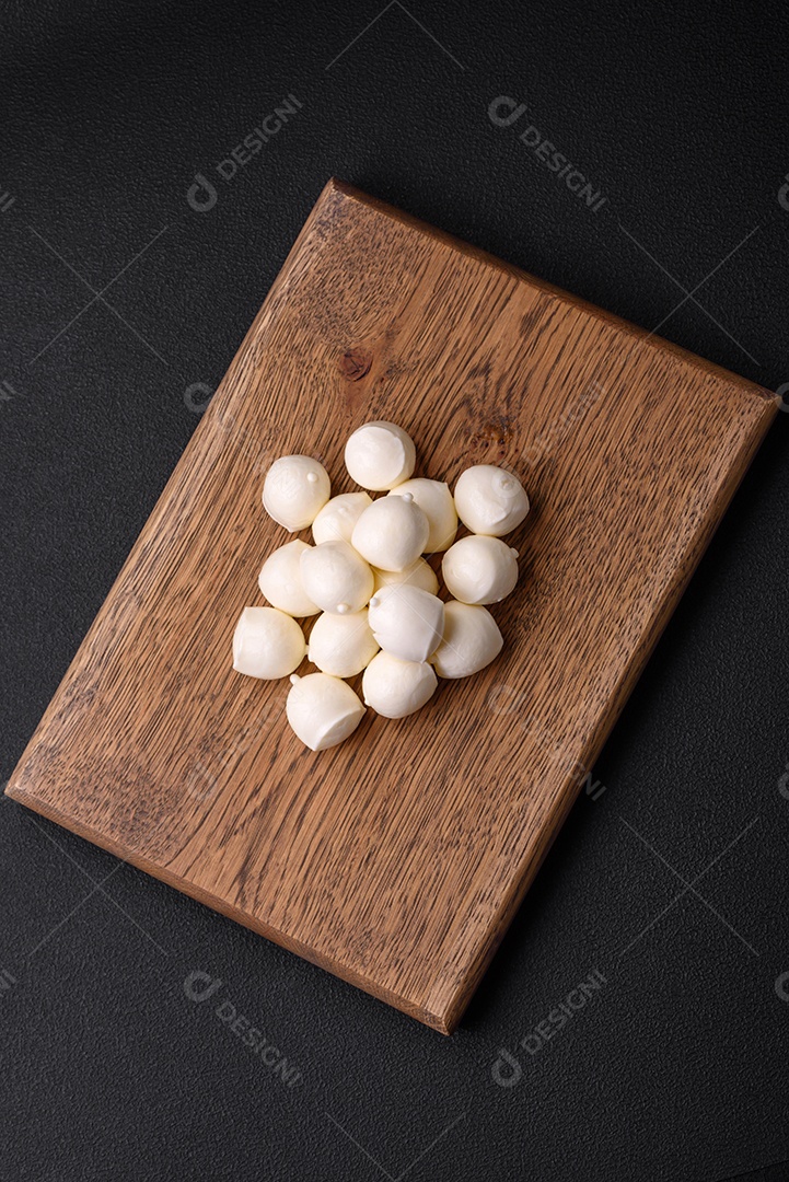 Delicioso queijo mussarela fresco em forma de bolinhas com sal e especiarias sobre fundo escuro de concreto