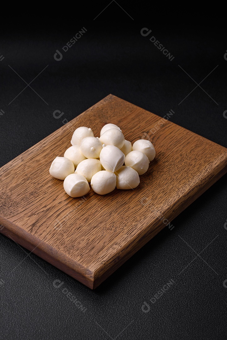 Delicioso queijo mussarela fresco em forma de bolinhas com sal e especiarias sobre fundo escuro de concreto