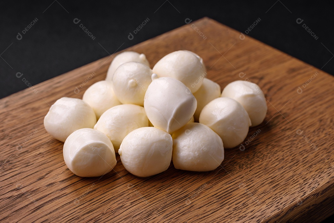 Delicioso queijo mussarela fresco em forma de bolinhas com sal e especiarias sobre fundo escuro de concreto