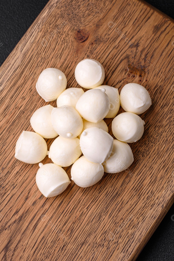 Delicioso queijo mussarela fresco em forma de bolinhas com sal e especiarias sobre fundo escuro de concreto