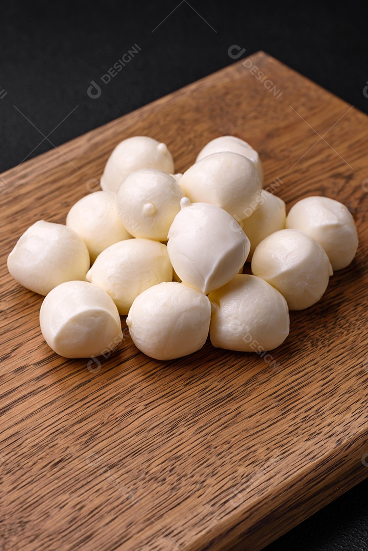 Delicioso queijo mussarela fresco em forma de bolinhas com sal e especiarias sobre fundo escuro de concreto
