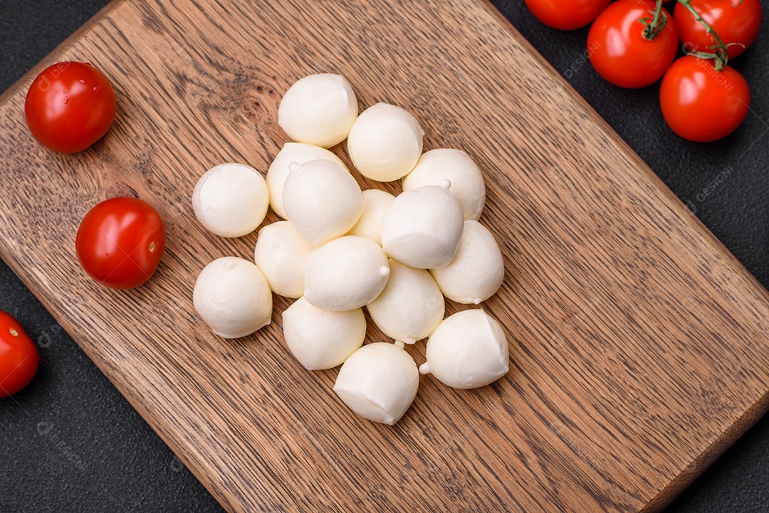 Delicioso queijo mussarela fresco em forma de bolinhas com sal e especiarias sobre fundo escuro de concreto