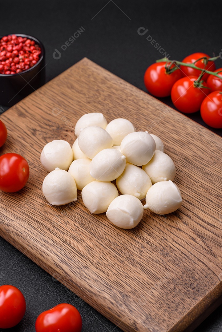 Delicioso queijo mussarela fresco em forma de bolinhas com sal e especiarias sobre fundo escuro de concreto