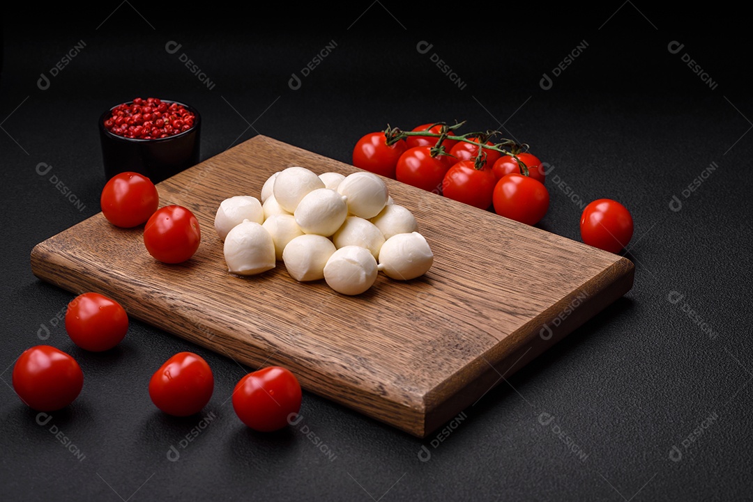 Delicioso queijo mussarela fresco em forma de bolinhas com sal e especiarias sobre fundo escuro de concreto