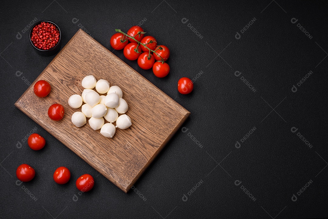 Delicioso queijo mussarela fresco em forma de bolinhas com sal e especiarias sobre fundo escuro de concreto