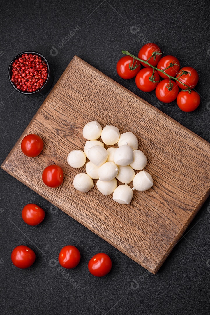 Delicioso queijo mussarela fresco em forma de bolinhas com sal e especiarias sobre fundo escuro de concreto