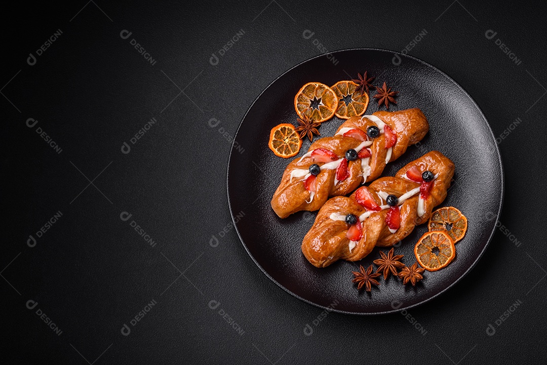Deliciosa massa crocante fresca em forma de trança com morangos e mirtilos sobre um fundo escuro de concreto