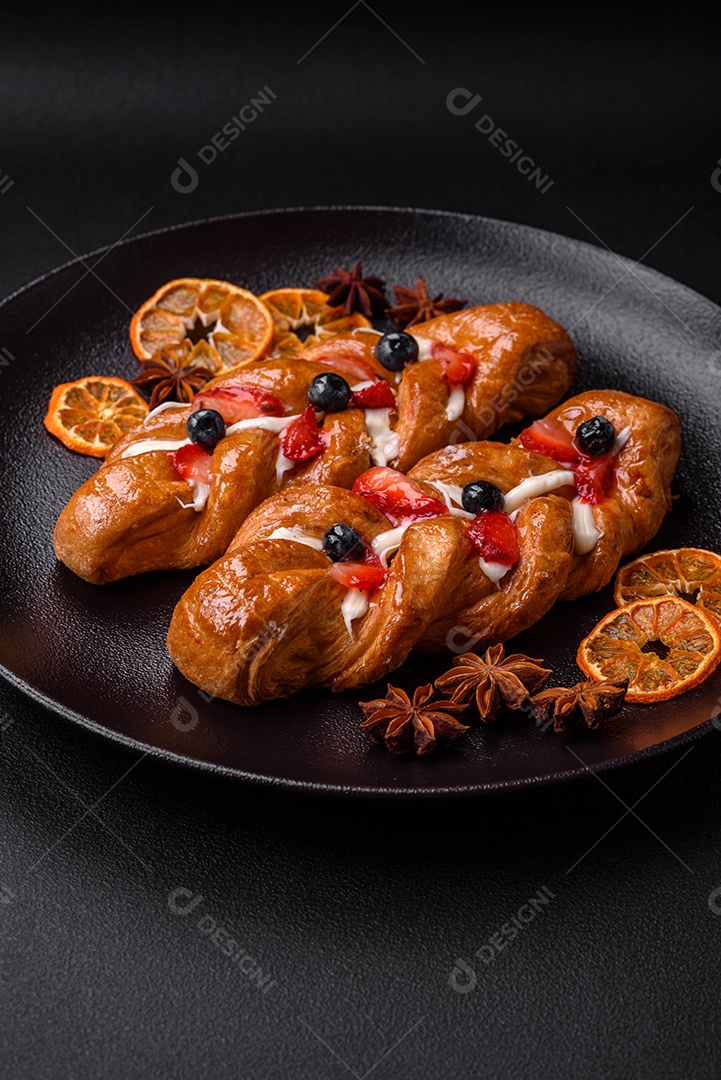 Deliciosa massa crocante fresca em forma de trança com morangos e mirtilos sobre um fundo escuro de concreto