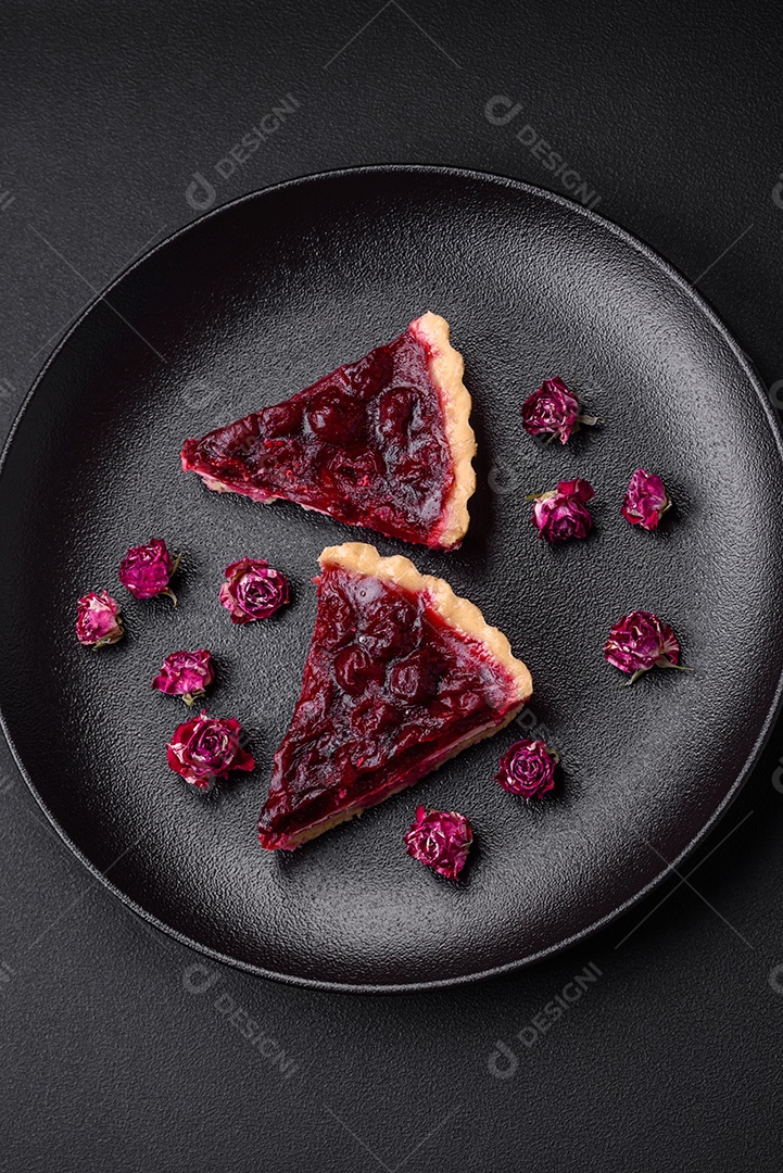 Deliciosa torta doce perfumada com bagas de cereja em uma placa de cerâmica sobre um fundo escuro de concreto