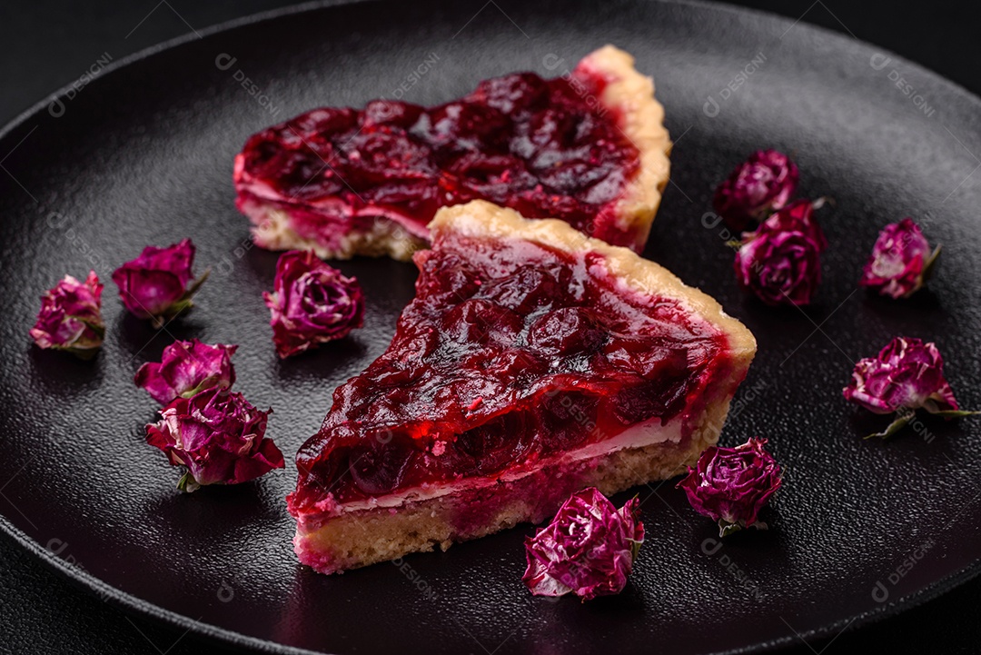Deliciosa torta doce perfumada com bagas de cereja em uma placa de cerâmica sobre um fundo escuro de concreto