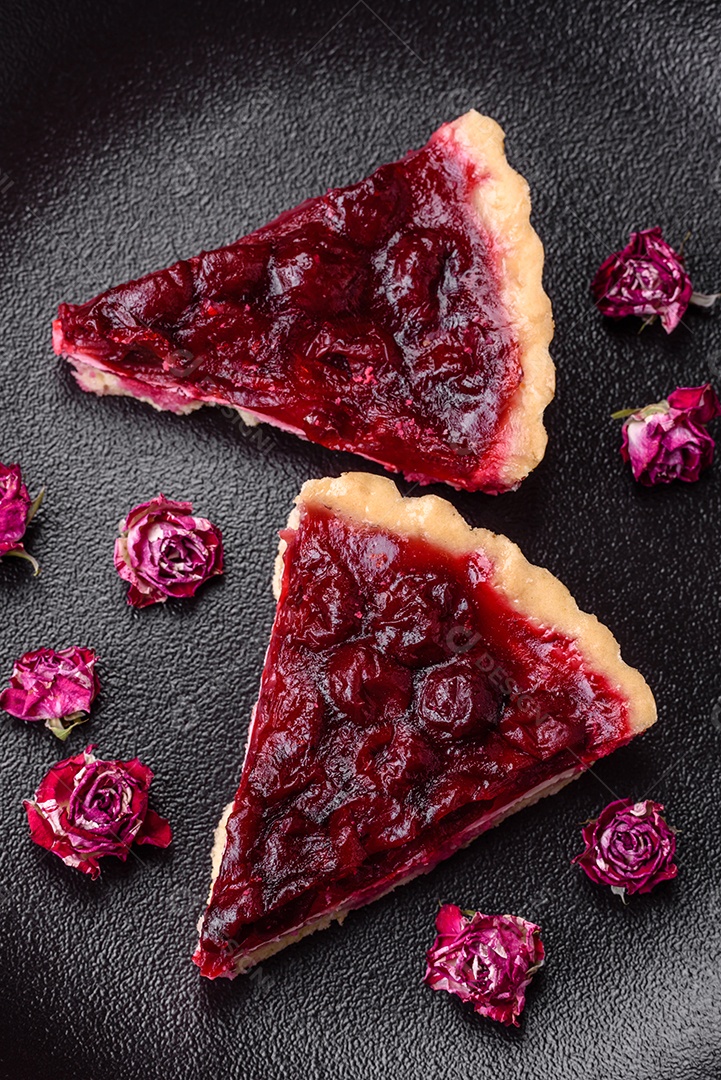 Deliciosa torta doce perfumada com bagas de cereja em uma placa de cerâmica sobre um fundo escuro de concreto