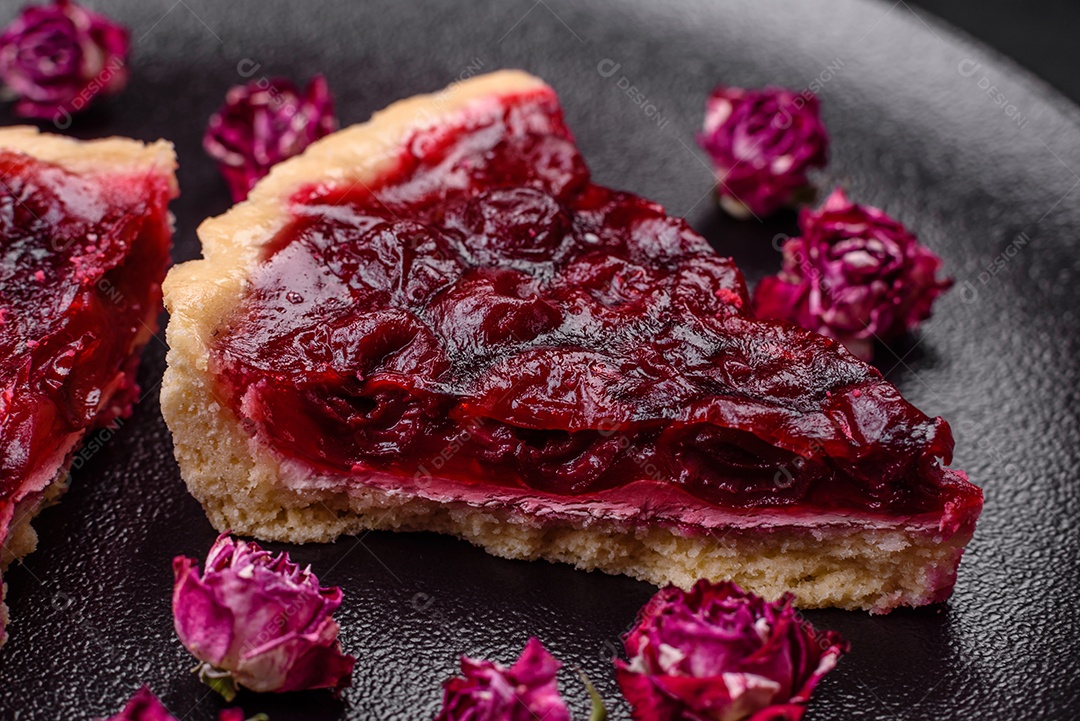 Deliciosa torta doce perfumada com bagas de cereja em uma placa de cerâmica sobre um fundo escuro de concreto