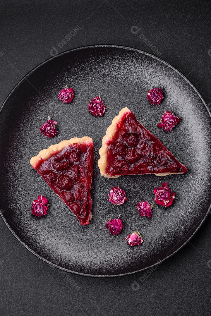 Deliciosa torta doce perfumada com bagas de cereja em uma placa de cerâmica sobre um fundo escuro de concreto