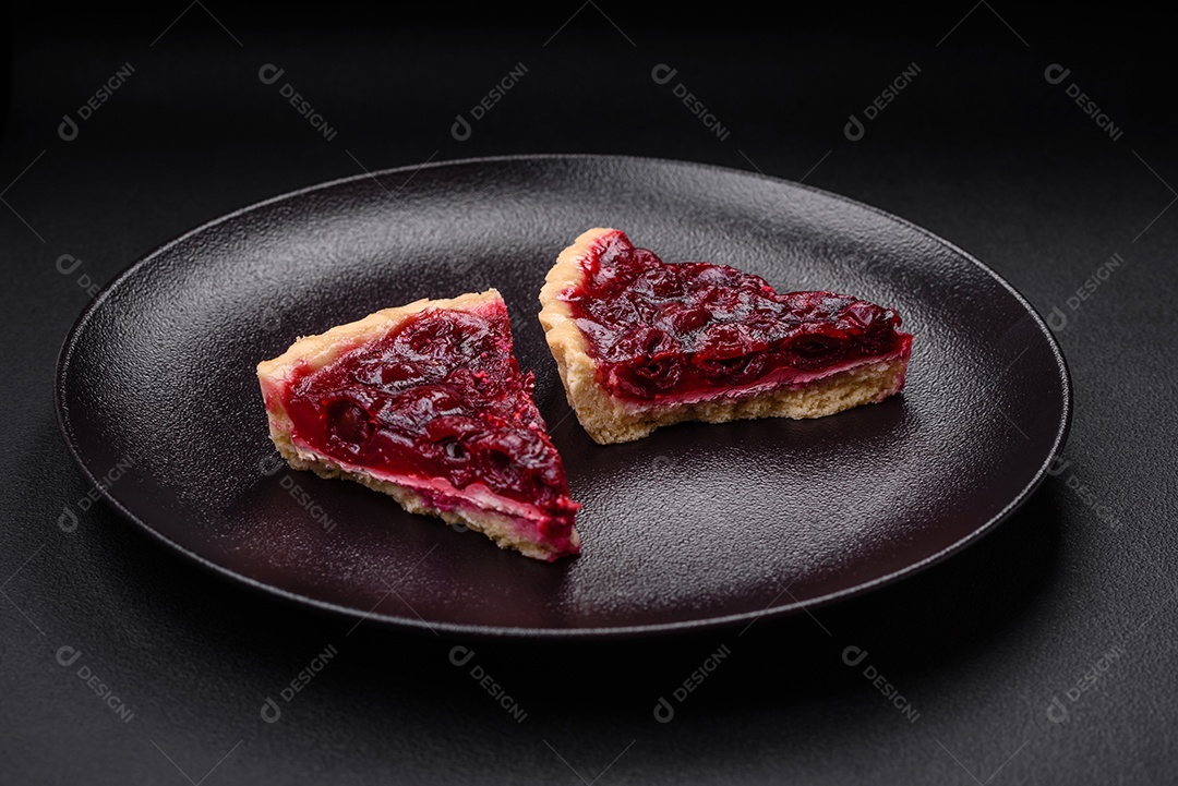 Deliciosa torta doce perfumada com bagas de cereja em uma placa de cerâmica sobre um fundo escuro de concreto