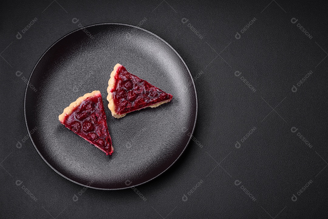 Deliciosa torta doce perfumada com bagas de cereja em uma placa de cerâmica sobre um fundo escuro de concreto